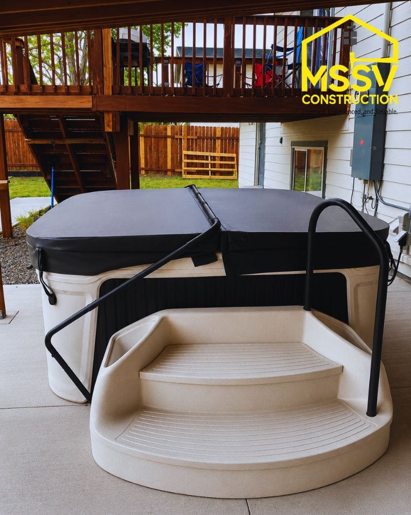 Outdoor hot tub with entry steps installed beneath a covered backyard deck