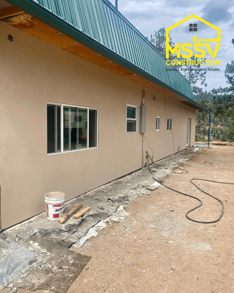 Completed stucco exterior on a residential home with a green metal roof