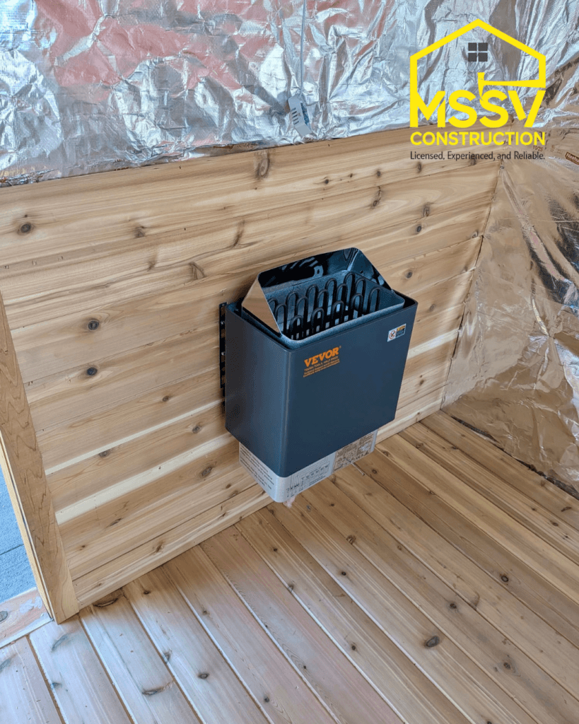 Indoor cedar sauna under construction with wall-mounted electric sauna heater