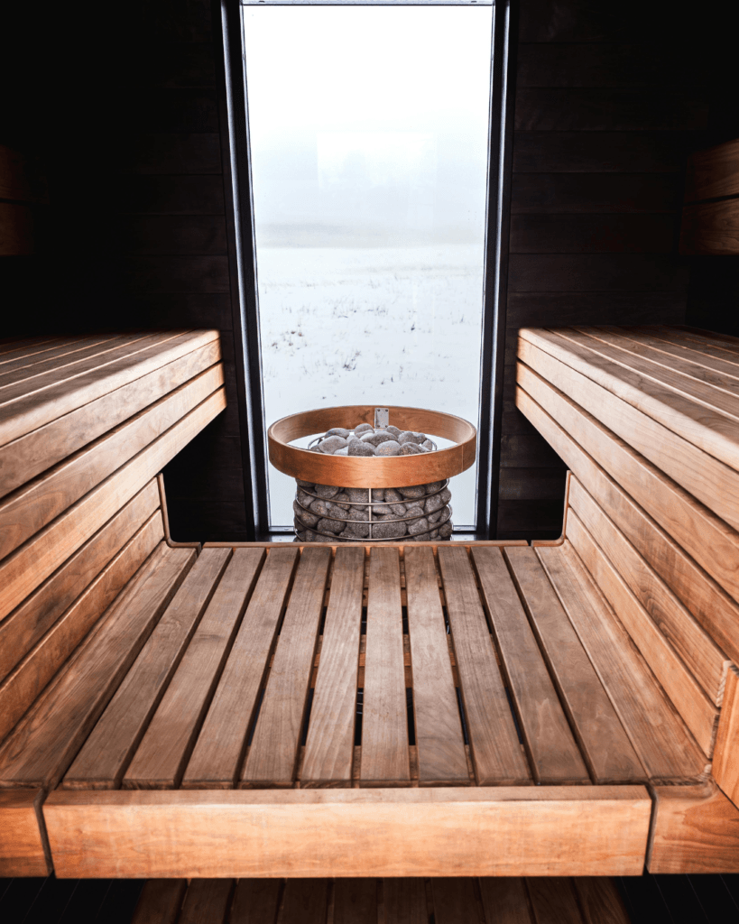Modern cedar sauna interior with wooden benches and a central stone sauna heater