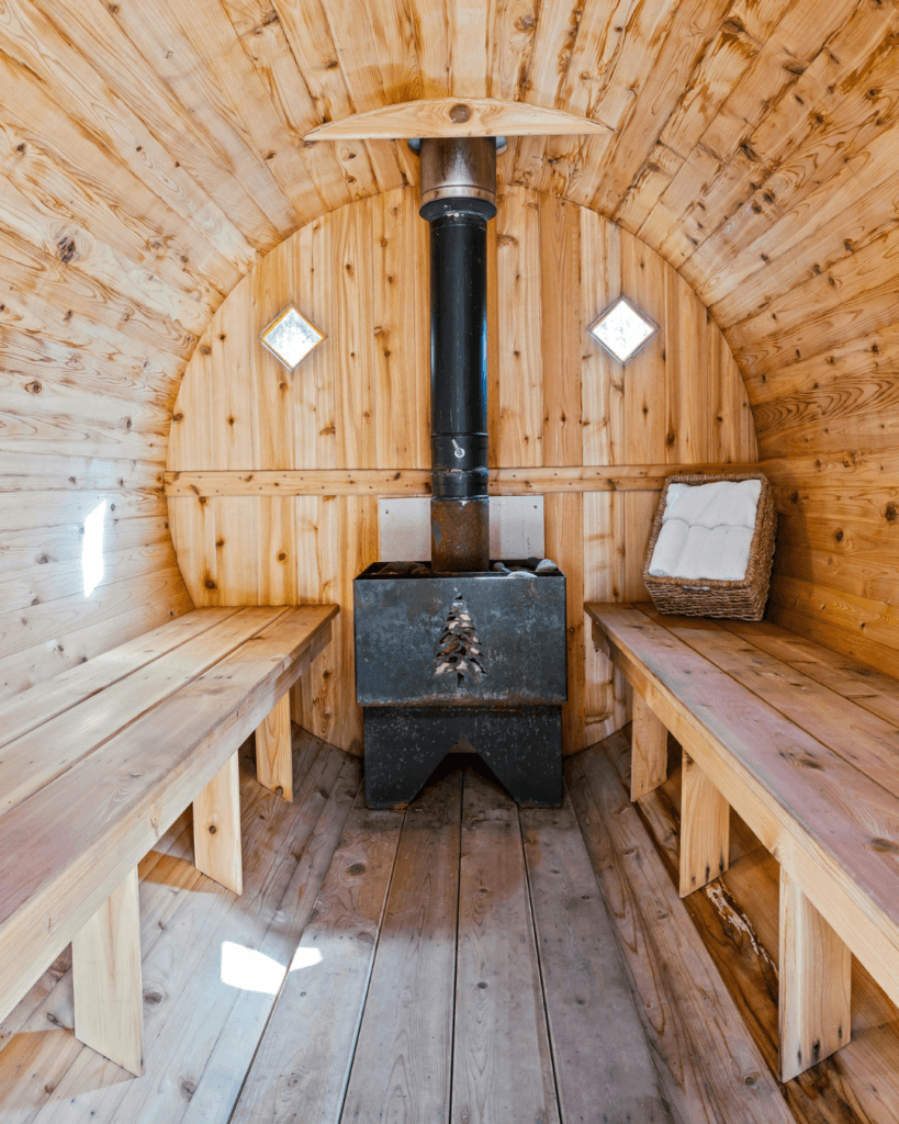 Barrel sauna interior with wood-burning stove and cedar benches