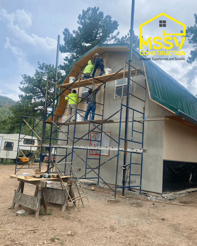Construction team installing exterior stucco on a custom home with scaffolding
