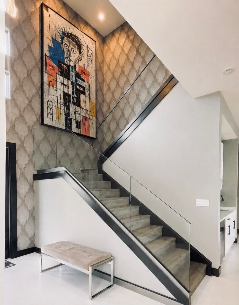 Modern staircase with glass railing, black trim and statement artwork