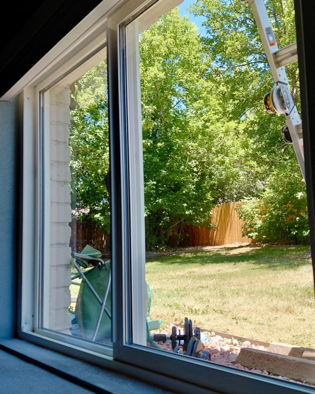 New energy-efficient sliding window installation overlooking a residential backyard