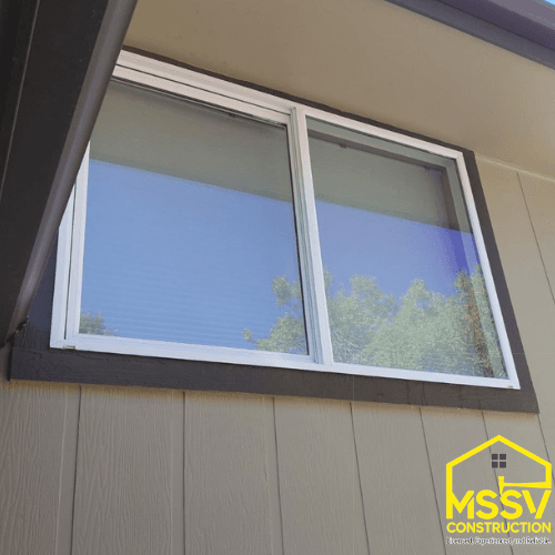 New white sliding window installed with dark exterior trim.