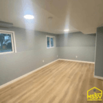 Finished basement remodel with gray walls, wood-look flooring, windows, and recessed lighting