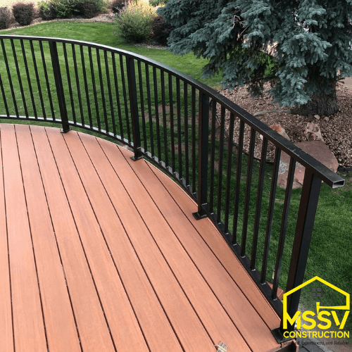 composite deck with curved black metal railing overlooking a landscaped backyard