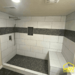Custom walk-in shower remodel with white tile, mosaic accents, built-in niche, and tiled bench