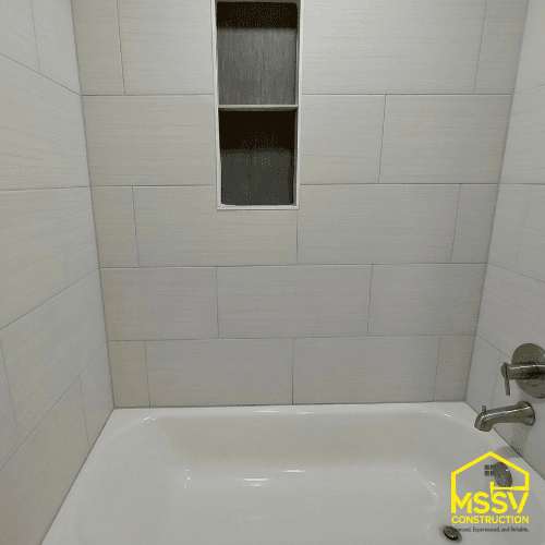 Modern bathtub and shower remodel with large-format tile and built-in wall niche