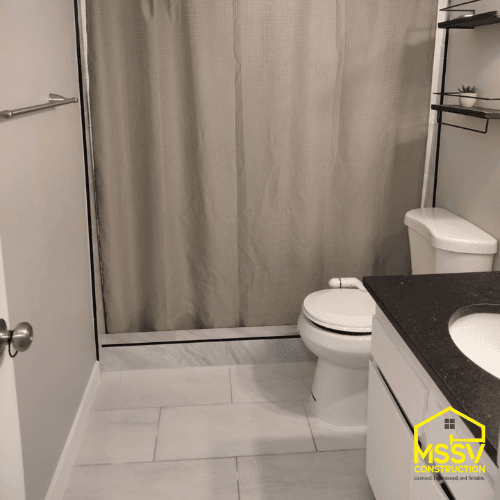 Completed bathroom remodel with bathtub, white tile flooring, toilet, and modern vanity