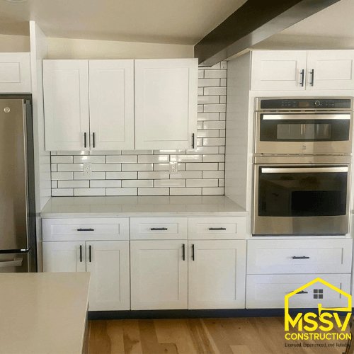 Modern kitchen remodel with white cabinets, tile backsplash and double wall oven