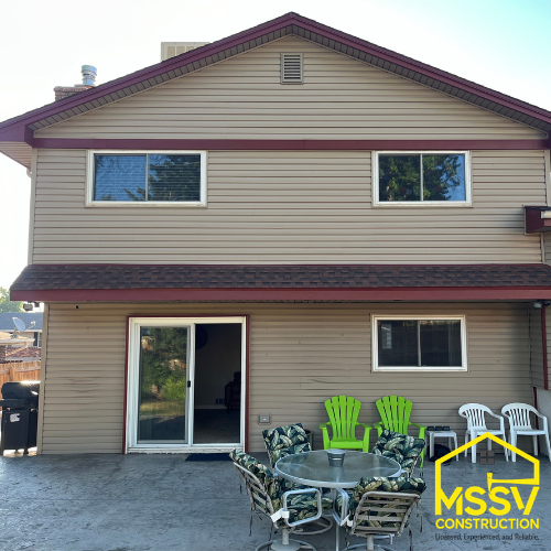 Two-story home exterior with beige siding, sliding patio door and backyard seating