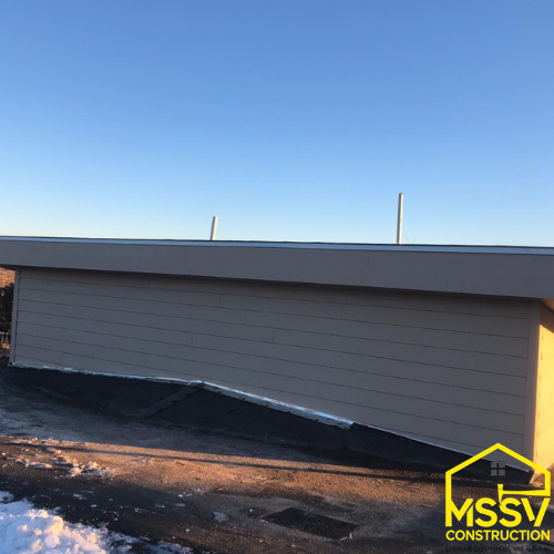 Close-Up of a residential roof edge and exterior wall beneath a clear blue sky.