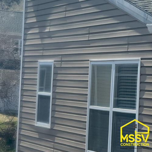Brown horizontal house siding with white-trimmed windows and sliding glass door